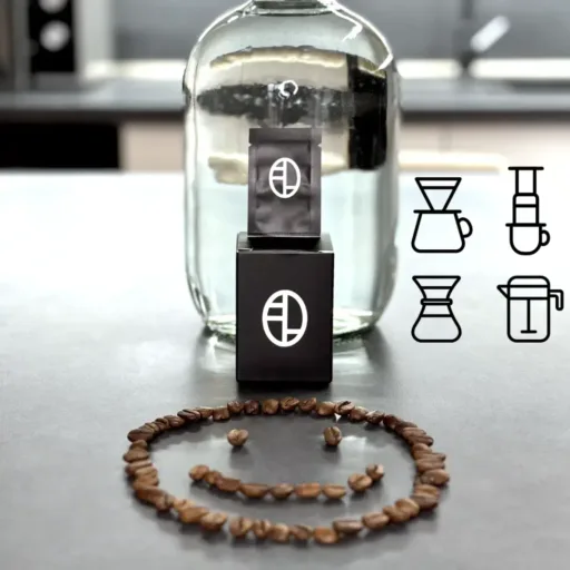 Specialty filter coffee water mineral pack next to a glass jug and smiley made from coffee beans, designed for pour-over brewing