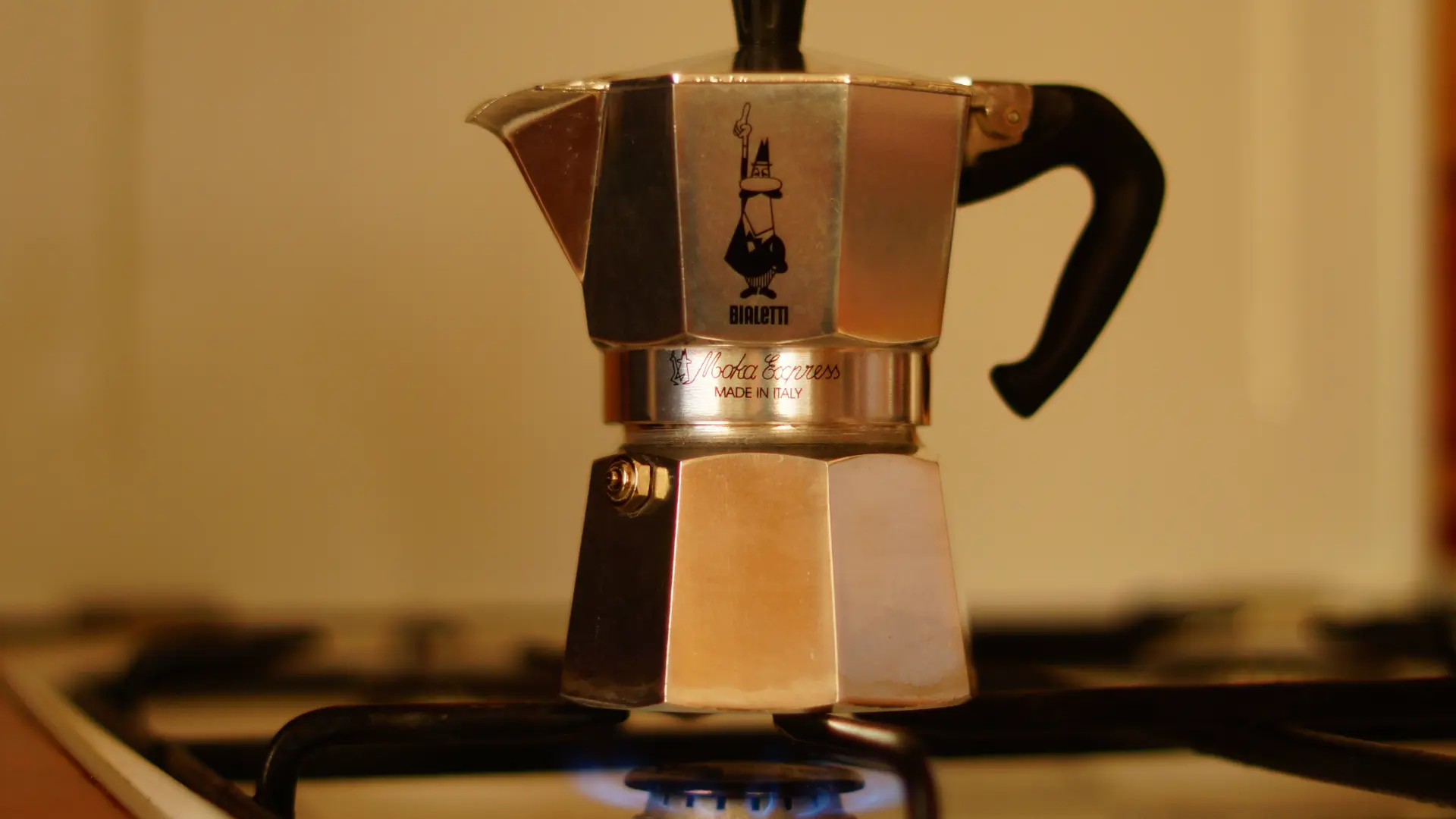 A classic silver Bialetti moka pot brewing espresso on a blue gas stove flame, illustrating Italy's historical dominance in global coffee and daily home brewing culture.